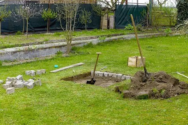 Stavba betonového ohniště v zahradě s nástroji a cihlami.