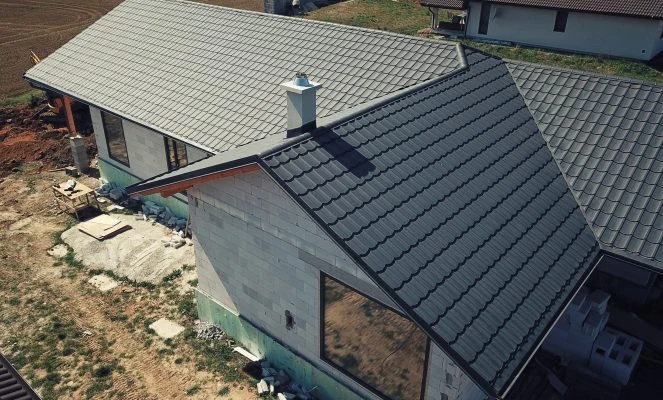 Dům s komínem oplechovaným šedými taškami při stavbě.