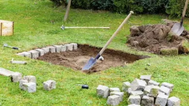 Stavba kamenného ohniště s nástroji na trávníku.
