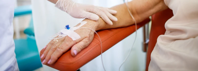 Zdravotník aplikuje kanylu na paži pacienta při odběru krve.