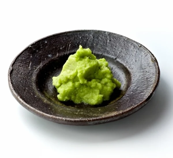 Hromada zelené pasty z wasabi v tmavém keramickém talíři.