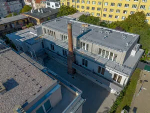 Pohled na revitalizovaný bytový dům s novou fasádou v městském prostředí.