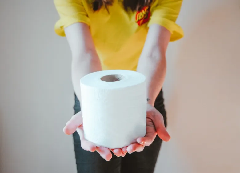 Těhotná žena drží toaletní papír v rukou.