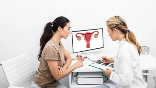 Lékařka vysvětluje pacientce příznaky rakoviny dělohy s obrázkem na obrazovce.