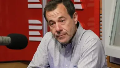 Muž mluví do mikrofonu v rozhlasové studiu.