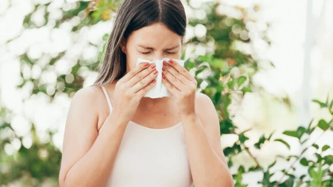 Woman sneezing with tissue