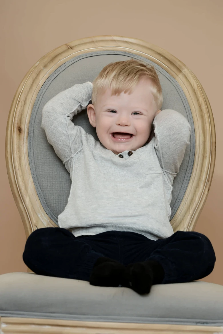 Usměvavé dítě s Downovým syndromem sedící v židli.