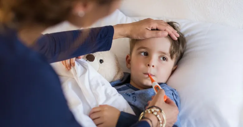 Dětský pacient s teploměrem v posteli, péče o subfebrilii