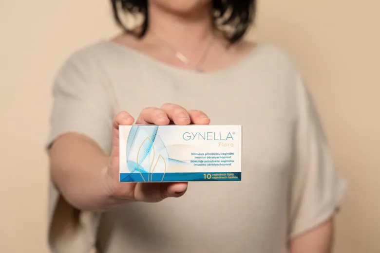 Žena drží krabičku s doplňkem pro vaginální zdraví značky Gynella.