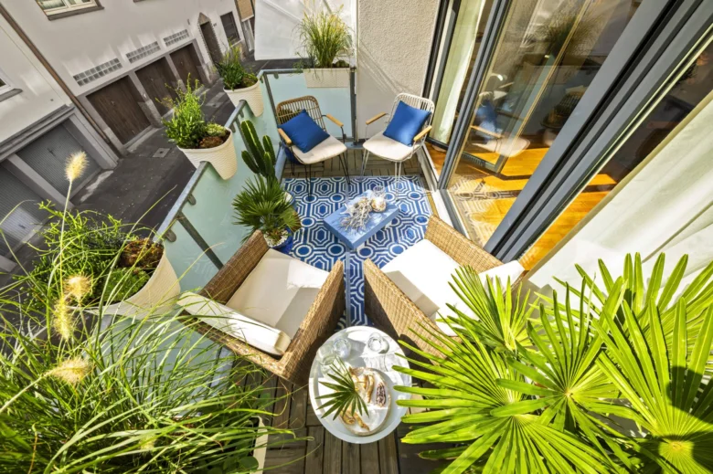 Balkon s různými rostlinami v květináčích a židlí.