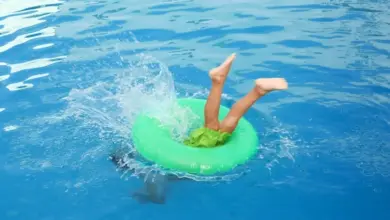 Dítě se houpá na nafukovacím kroužku v bazénu.