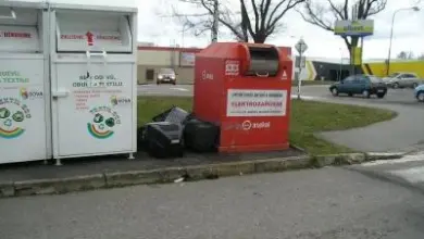 Bílé kontejnery na recyklaci vedle červeného kontejneru pro elektřiny odpady.