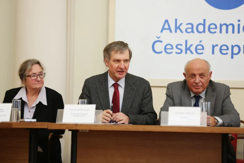 Tři lidé sedí za stolem na konferenci v Česku.