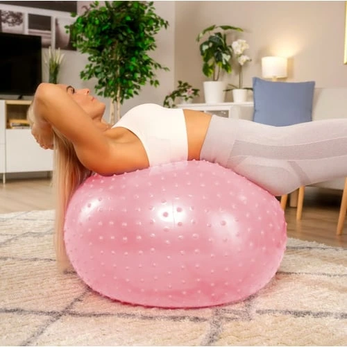 Žena cvičí na růžovém fitbalu pro bolest beder.