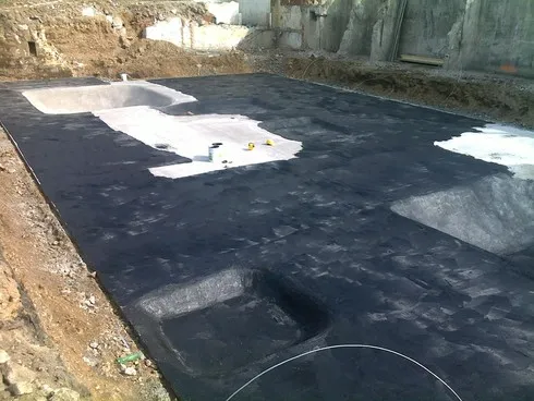 Práce s bitumovou stěrkou na izolaci podkladu.