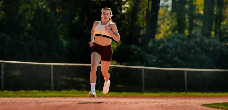 Žena běží na atletickém okruhu venku.