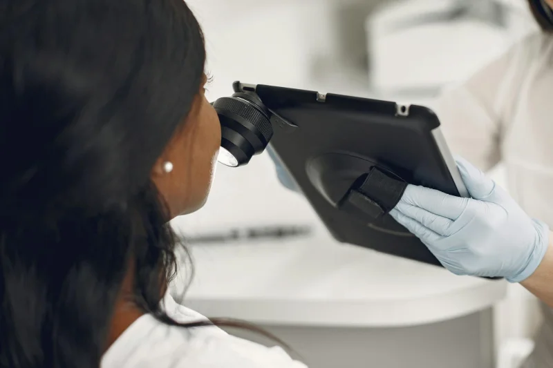 Dermatolog zkoumá kůži pacienta pomocí digitálního zařízení v ordinaci.