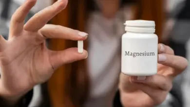 Bílá lahvička hořčíku s tabletou v ruce osoby.