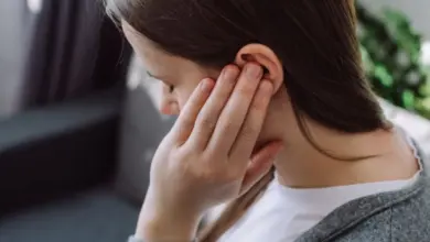 Žena drží ucho kvůli tínnitu nebo bolesti krční páteře.