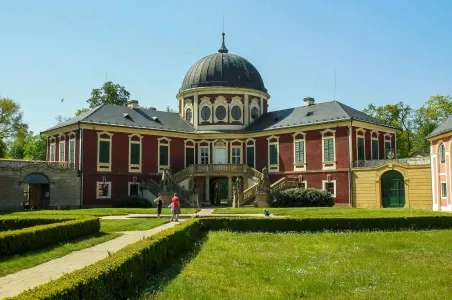 Zámek Veltrusy s kupolí a úhlednou zahradou.