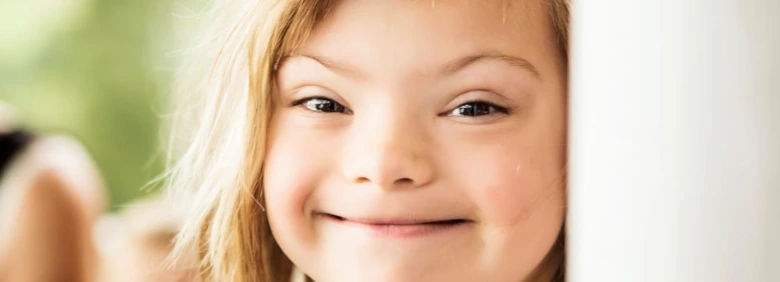 Usměvavé dítě s Downovým syndromem se zlatými vlasy.