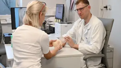 Lékař ukazuje pacientce silikonový model prsu během konzultace.