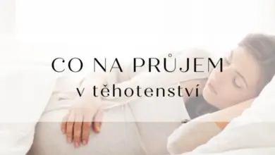 Těhotná žena spí v posteli a drží si břicho.