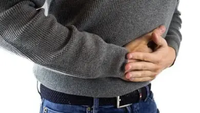 Muž drží žaludek v bolesti při trávicích potížích.