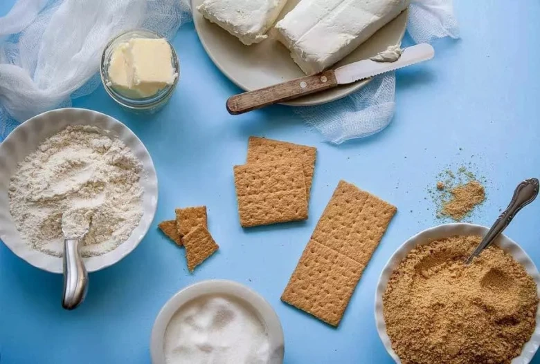Suroviny na bezlepkové pečení rozložené na modrém povrchu.