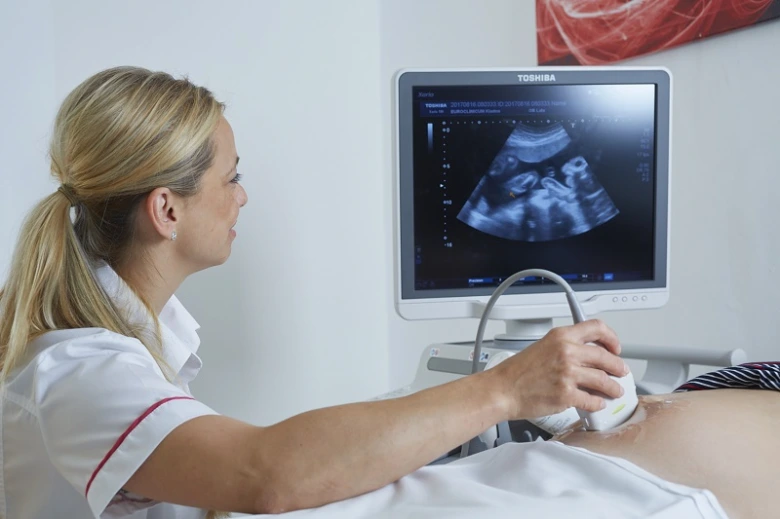 Gynekologka provádí ultrazvukové vyšetření pacientce v ordinaci.