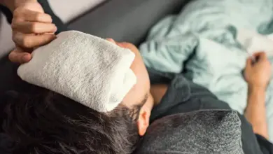 Osoba s chladným obkladem na čele pro snížení horečky.