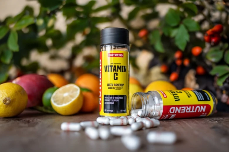 Doplňkový vitamín C s ovocem na dřevěném povrchu.