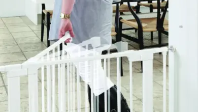 Žena otevírá bílou bezpečnostní branku na schodech do kuchyně.