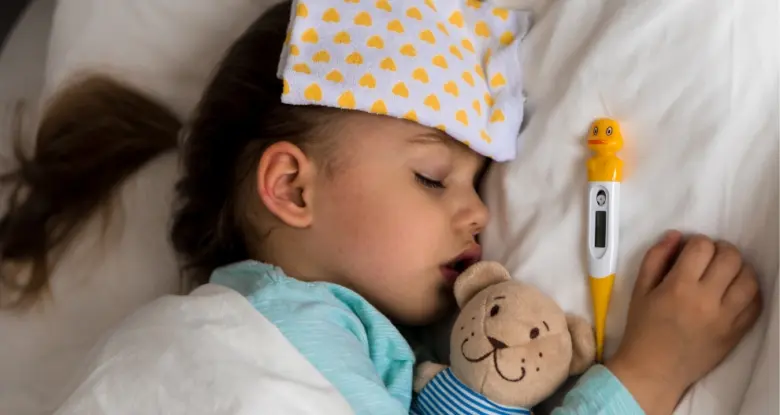 Spící nemocná dívka s teploměrem v posteli.