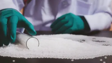 Vědec v laboratoři sypavý bílé polymerní kuličky z sklenice.