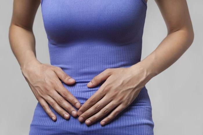 Žena drží ruce na břiše kvůli inkontinenci