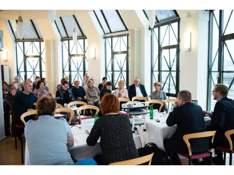 Skupina lidí sedících v konferenčním sále během diskuse.
