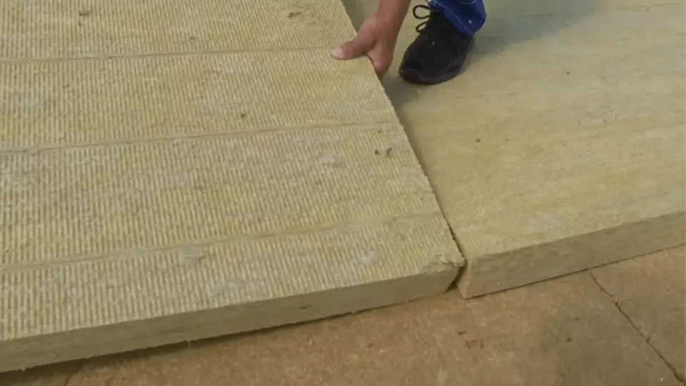 Montáž izolačních desek na plochou střechu rukama pracovníka.