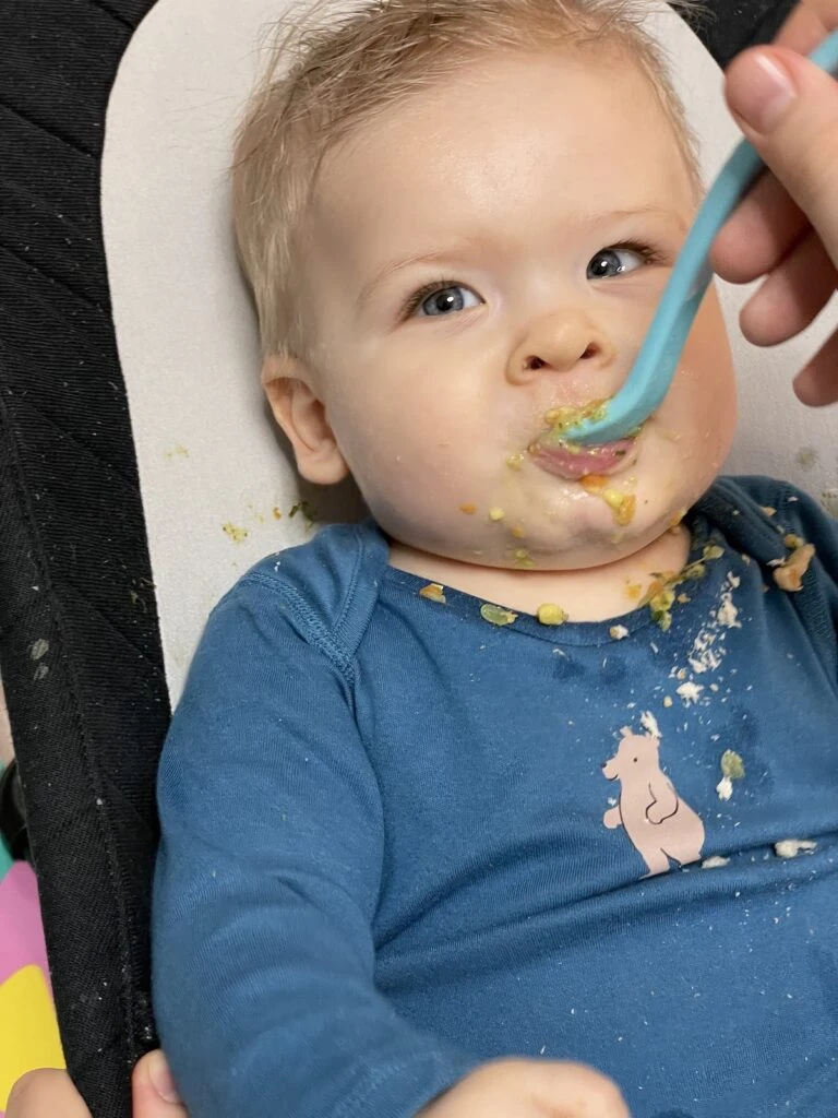 Babička se krmití kašičkou z lžičky při BLW metodě.