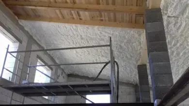 Bílá pěnová izolace stropu v nevytápěné místnosti během stavby.