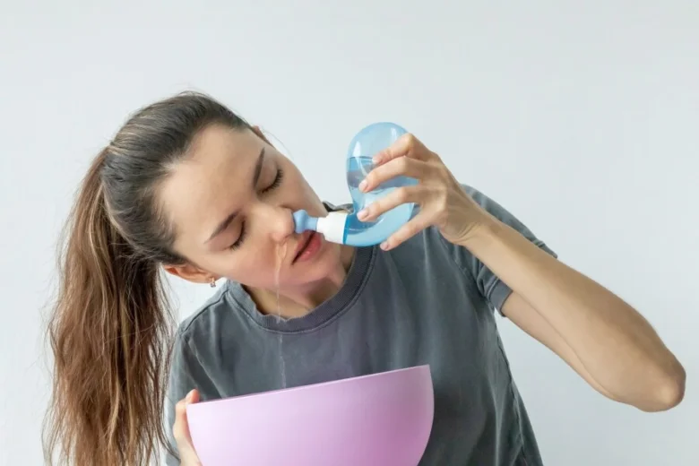 Žena používá nosní zavlažování k uvolnění ucpaného nosu bez léků.