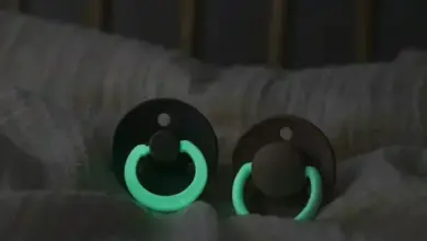 Dvě svítící dudlíky na posteli v tmě.