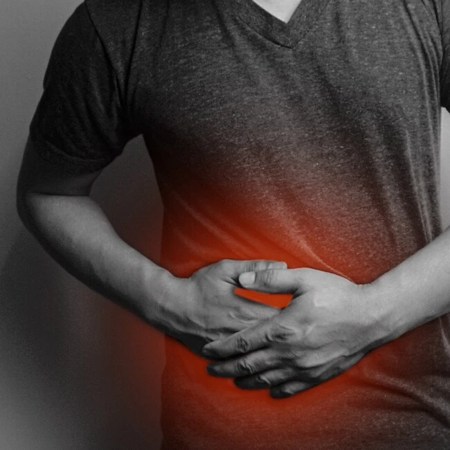 Muž drží břicho v bolesti - příznaky žlučníku.