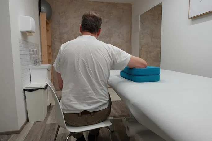 Muž cvičí rameno na rehabilitaci v ordinaci.