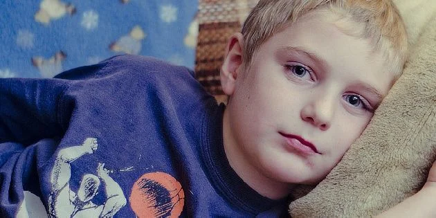 Mladý chlapec leží na polštáři s vyjadřující tvář.