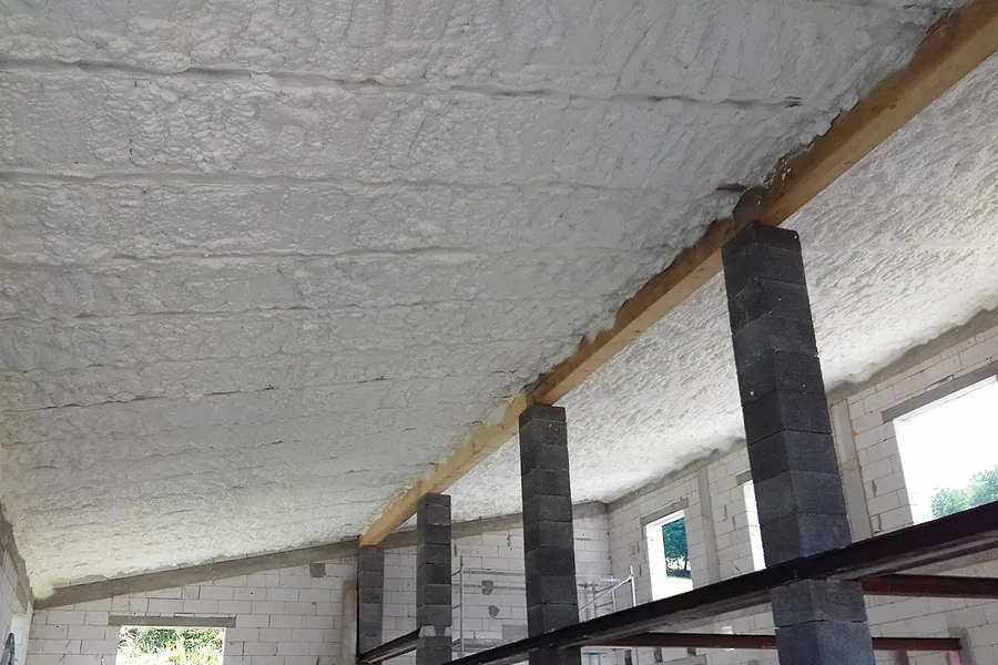 Nabíjený strop v nevytápěné místnosti s bílým izolačním pěnovým nátěrem.