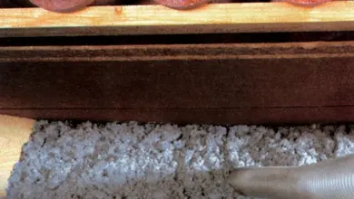 Bílá celulóza se vstřikuje do stěny mezi trámy pro tepelnou izolaci.