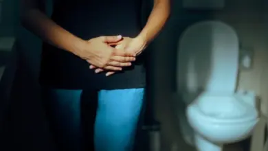 Žena v koupelně drží ruce na břiše kvůli hyperaktivnímu močovému měchýři.