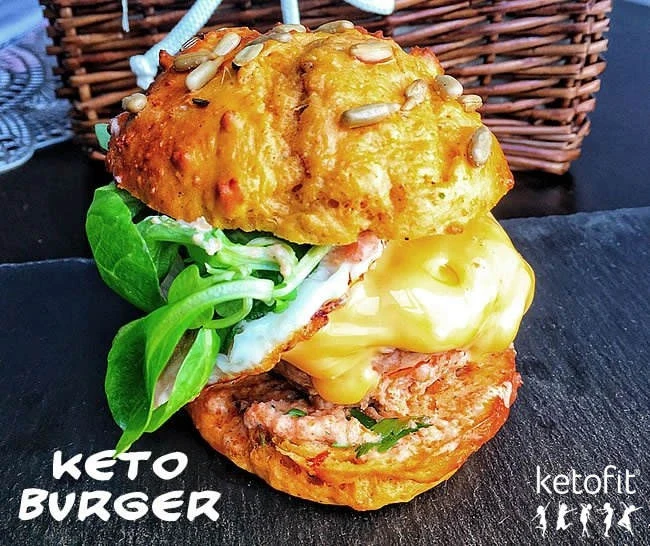 Nízkosacharidový hamburger se sýrem a zeleninou na tmavém podkladu.