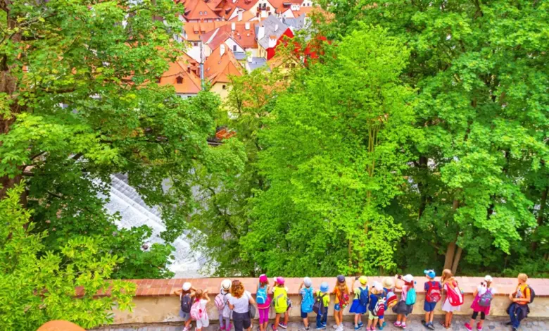 Skupina dětí s batohy hledí na české město z výhledu.